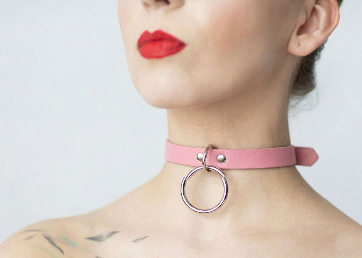 Kožený Choker C002 v ružovej farbe s visiacim strieborným krúžkom spája nežnosť s hravou provokáciou. Jemný na pohľad, no s nádychom šibalstva.